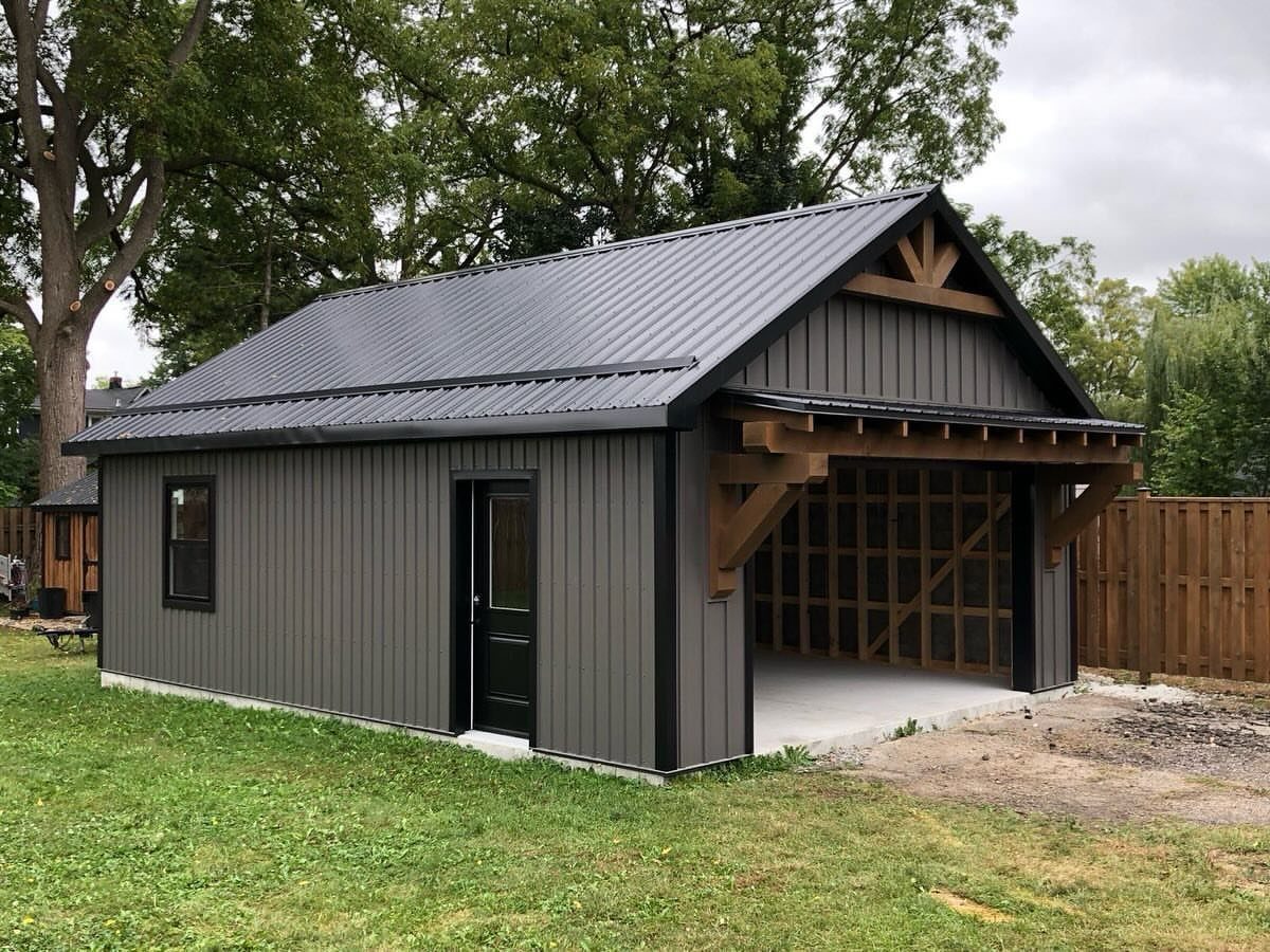 9 Shed Exterior Ideas: Metal, Wood, Recycled, and Garden Styles 1 A dark grey metal shed with vertical siding and a large open timber-framed garage area.