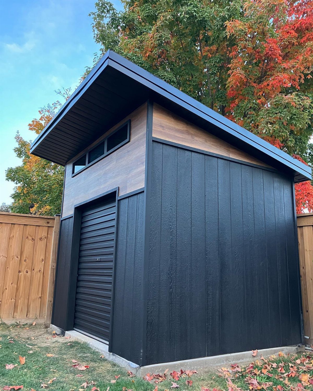 9 Shed Exterior Ideas: Metal, Wood, Recycled, and Garden Styles 2 A modern garden shed featuring black vertical siding and a natural wood siding accent section.
