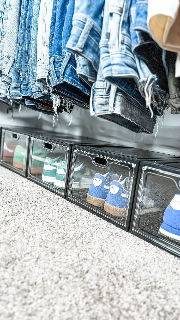 Small Sneaker Collection Closet: 5 Space-Smart Setups 5 Clear plastic sneaker storage boxes containing colorful shoes lined up on a carpeted floor under hanging jeans.