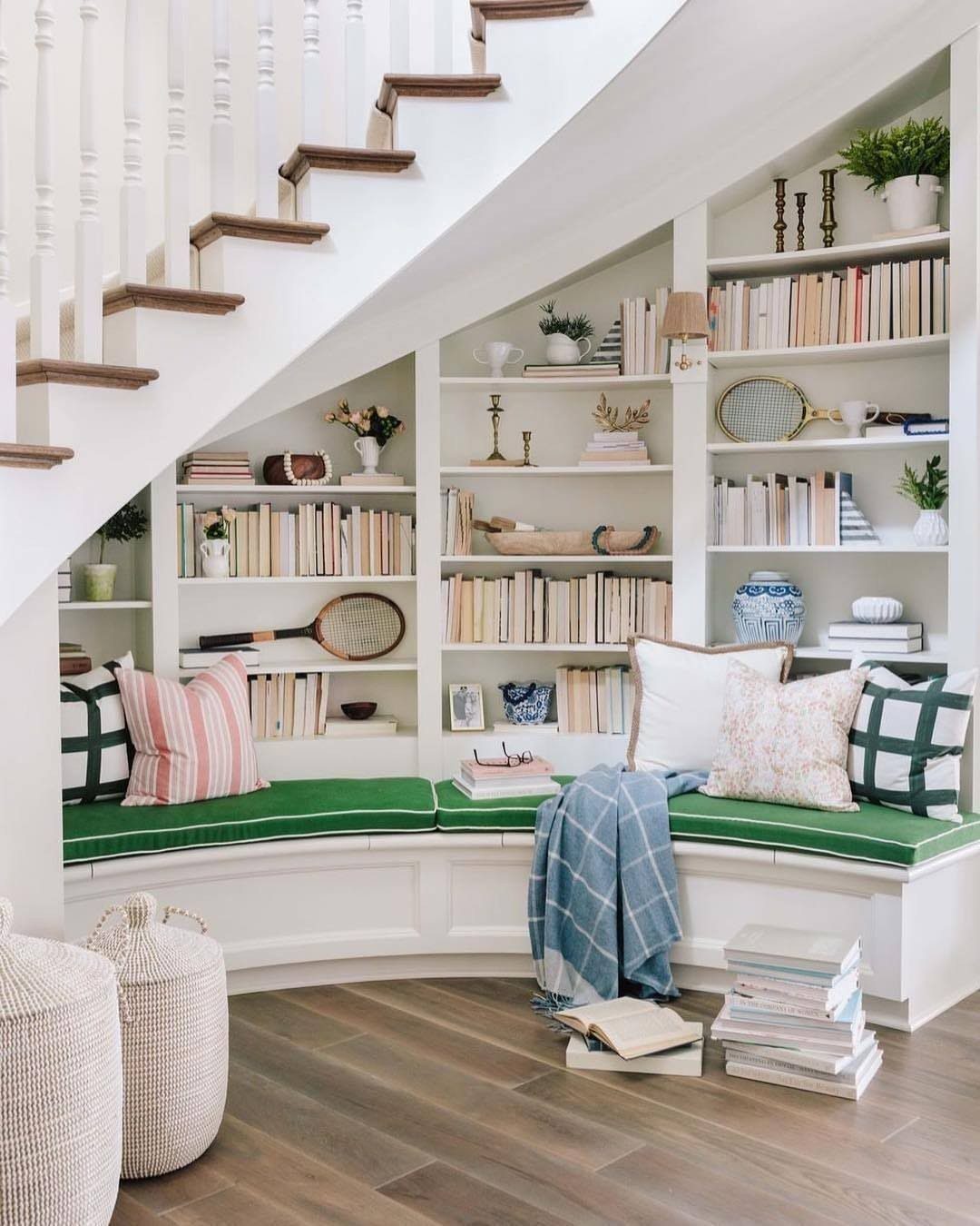 18 Under Stair Storage Design Modern Ideas for Every Home 1 White built-in bookshelves filled with books and decor under a staircase with a green bench.