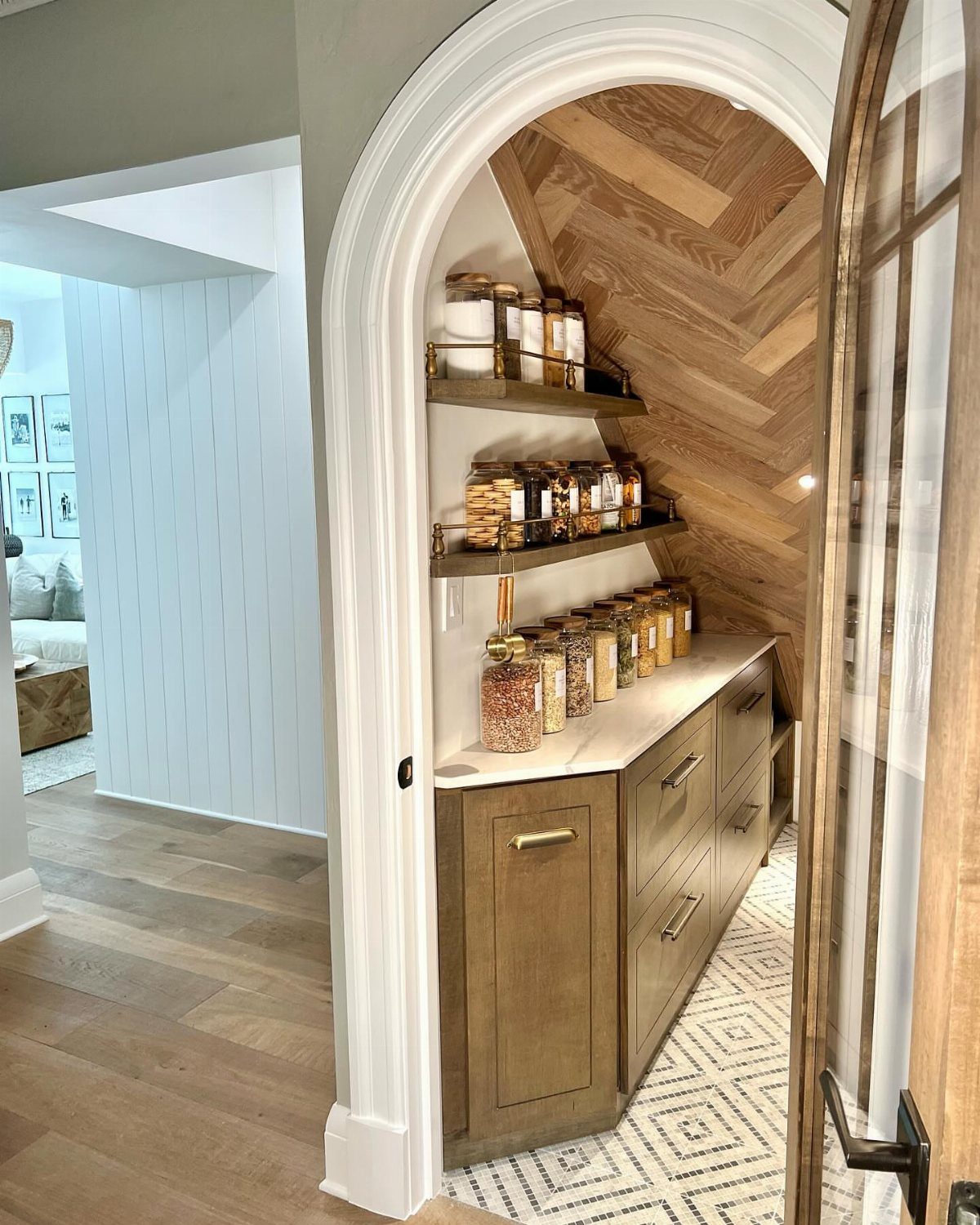 18 Under Stair Storage Design Modern Ideas for Every Home 12 Custom pantry with wooden cabinets and glass jars stored under a staircase archway.