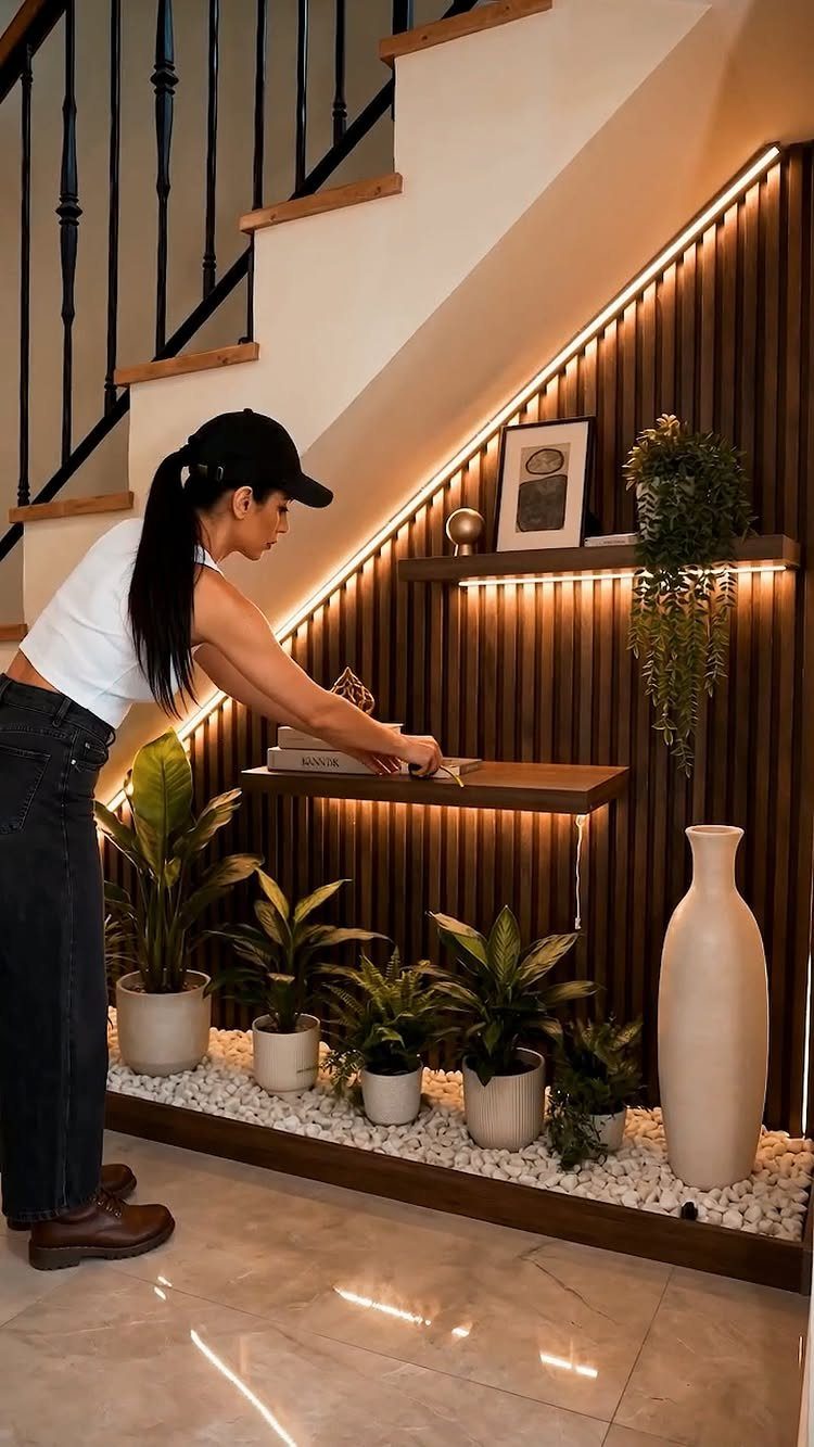 18 Under Stair Storage Design Modern Ideas for Every Home 16 Woman arranging books on a wooden shelf against a slatted wall under stairs.