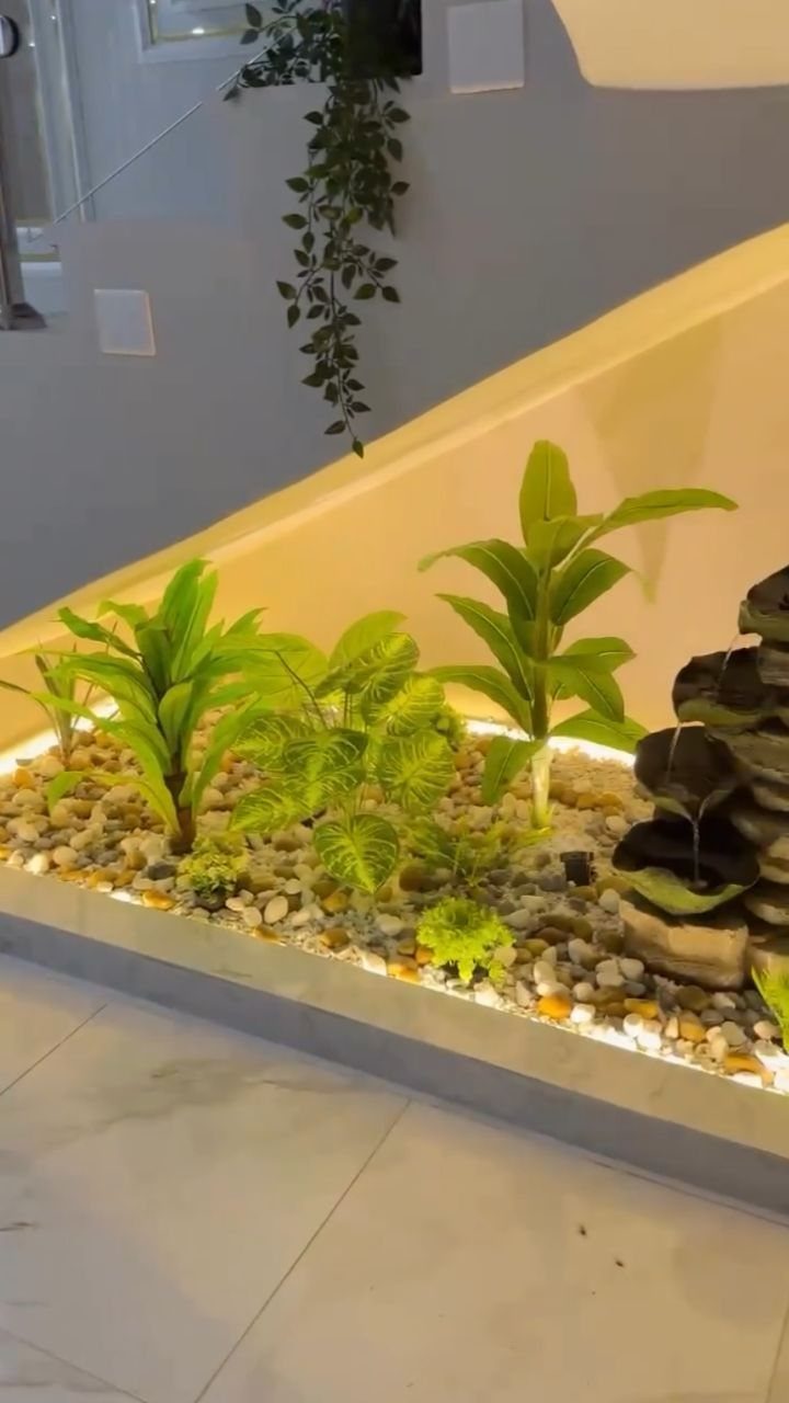 18 Under Stair Storage Design Modern Ideas for Every Home 17 Green plants growing in a pebble-filled garden bed located under a staircase.