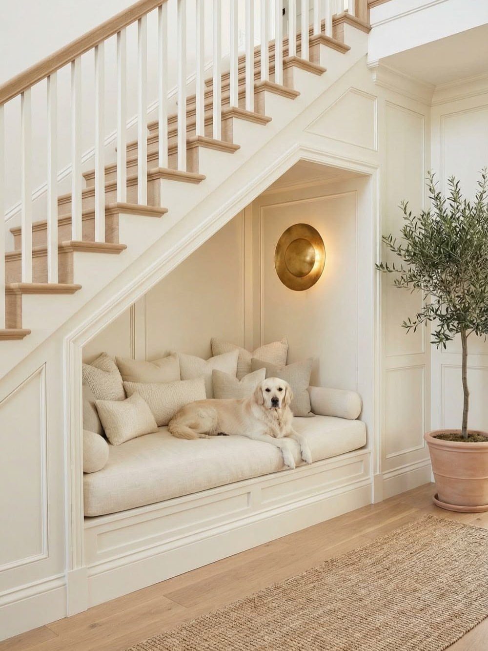18 Under Stair Storage Design Modern Ideas for Every Home 8 A cream-colored built-in reading nook under a staircase with a dog resting on the cushions.