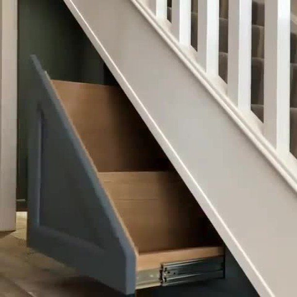 18 Under Stair Storage Design Modern Ideas for Every Home 11 A large grey drawer being pulled out from under a white staircase showing wooden interior.
