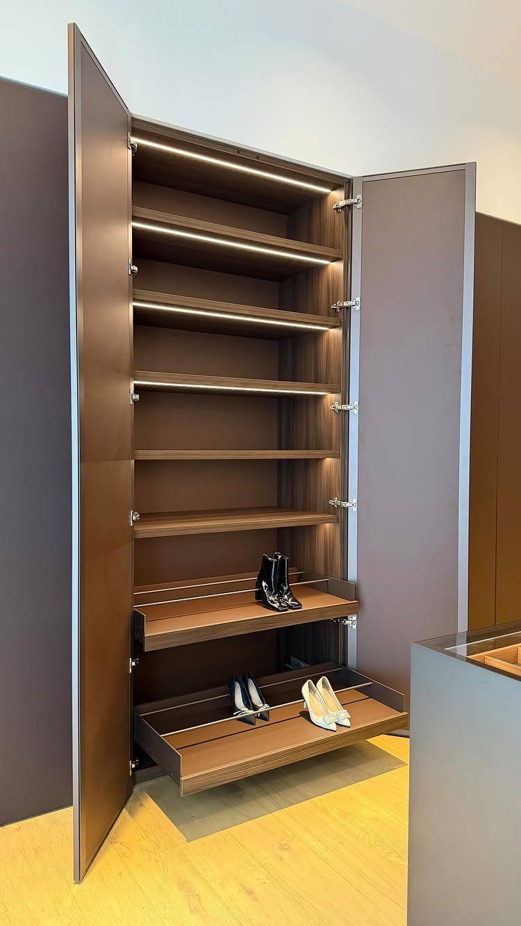 Dark wood built-in wardrobe with illuminated open shelves and pull-out shoe trays.