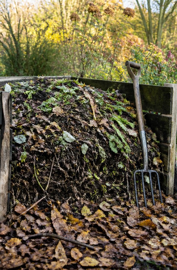 A compost pile layered with kitchen scraps and dried leaves.